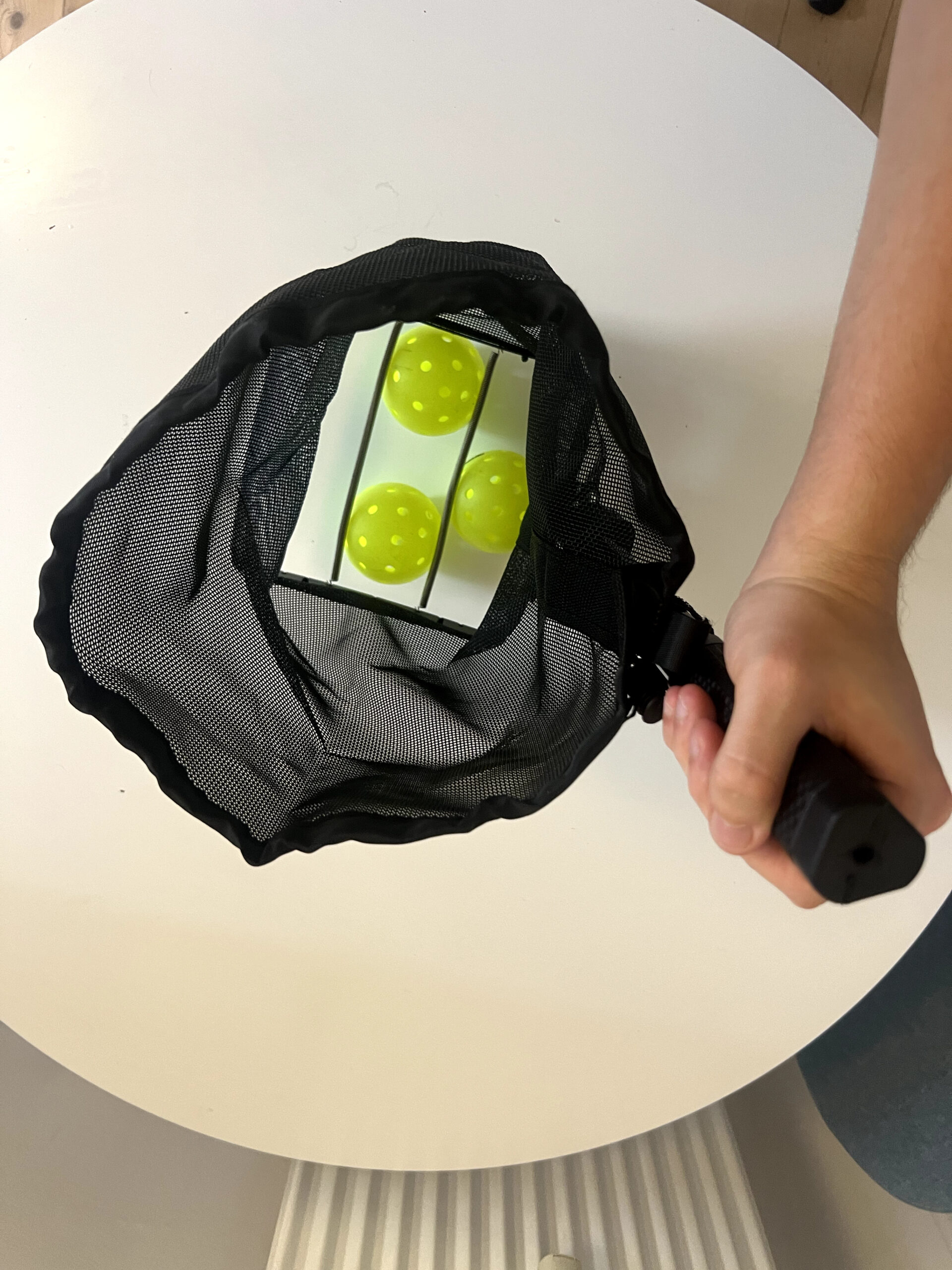 Recolhedor Retrora posicionado sobre uma bola de pickleball para recolhimento
