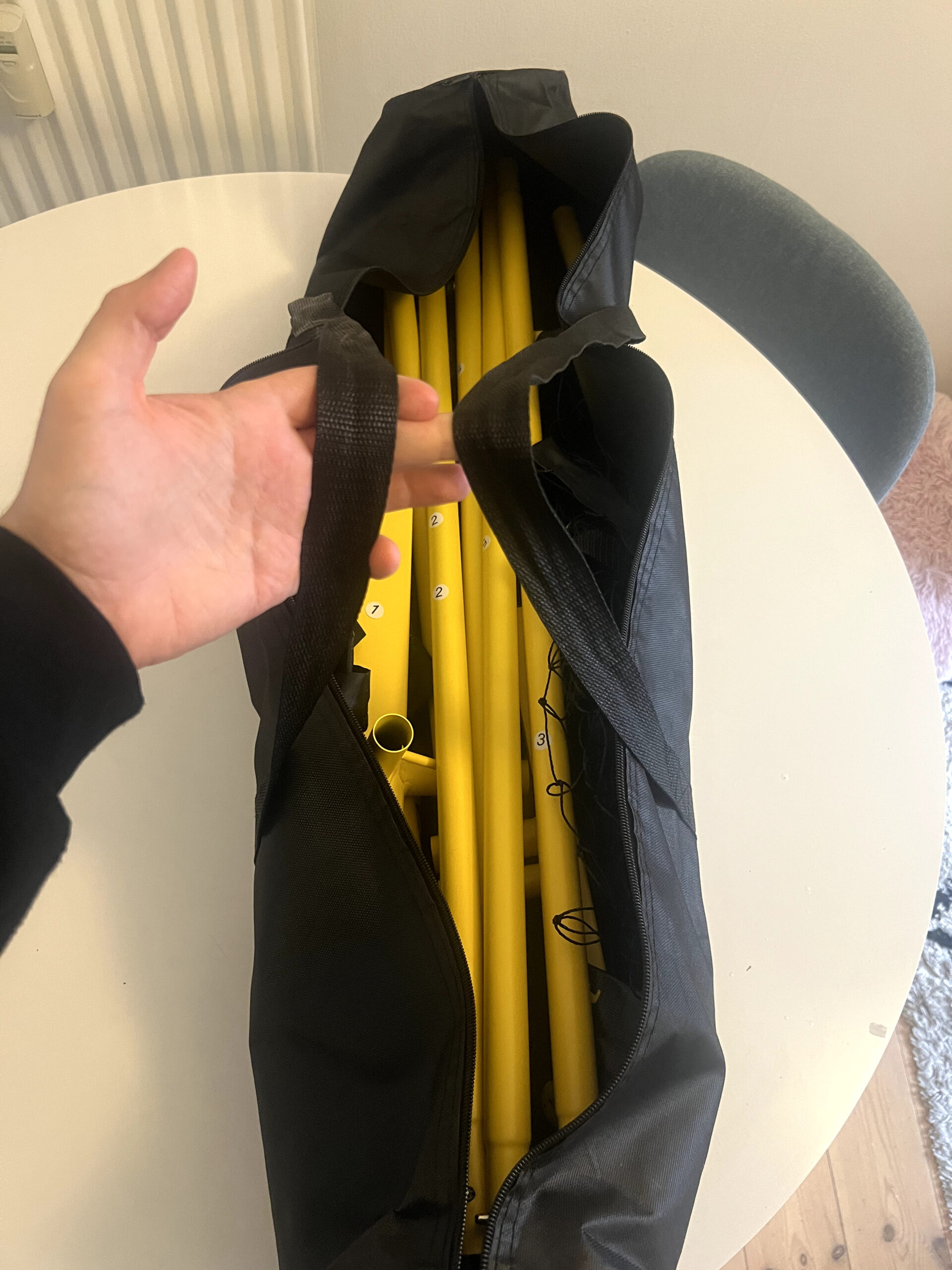 Fostoy-nätets delar nedpackade i bärväskan med axelrem