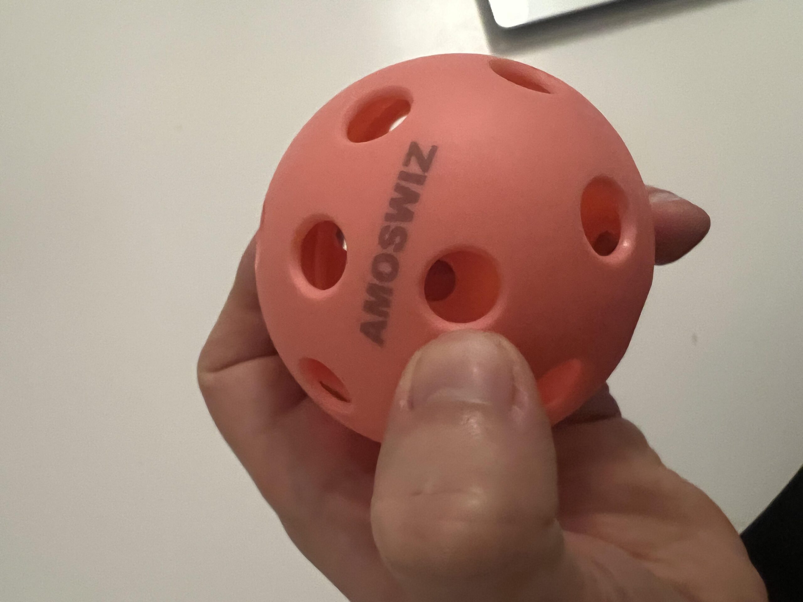 Bola AMOSWIZ rosa comprimida com a mão durante verificação de pressão informal
