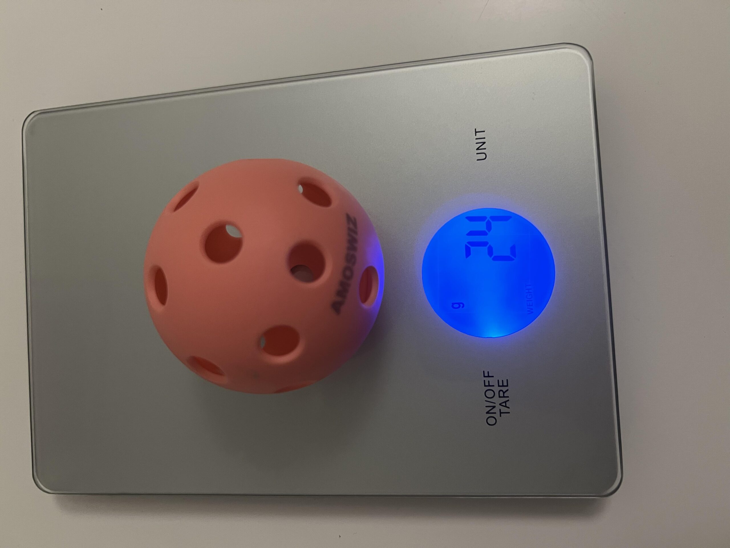 Bola AMOSWIZ rosa de 26 furos na balança digital marcando 24 gramas