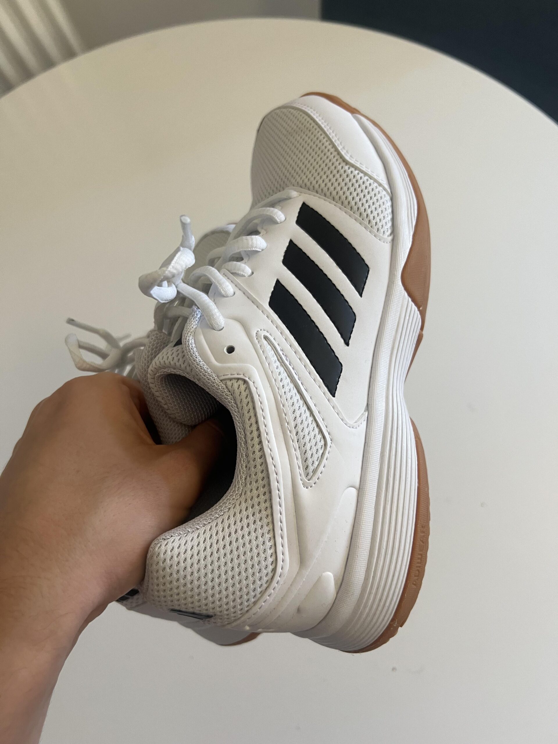 Side profile of white and black adidas Speedcourt indoor shoes with gum rubber outsole