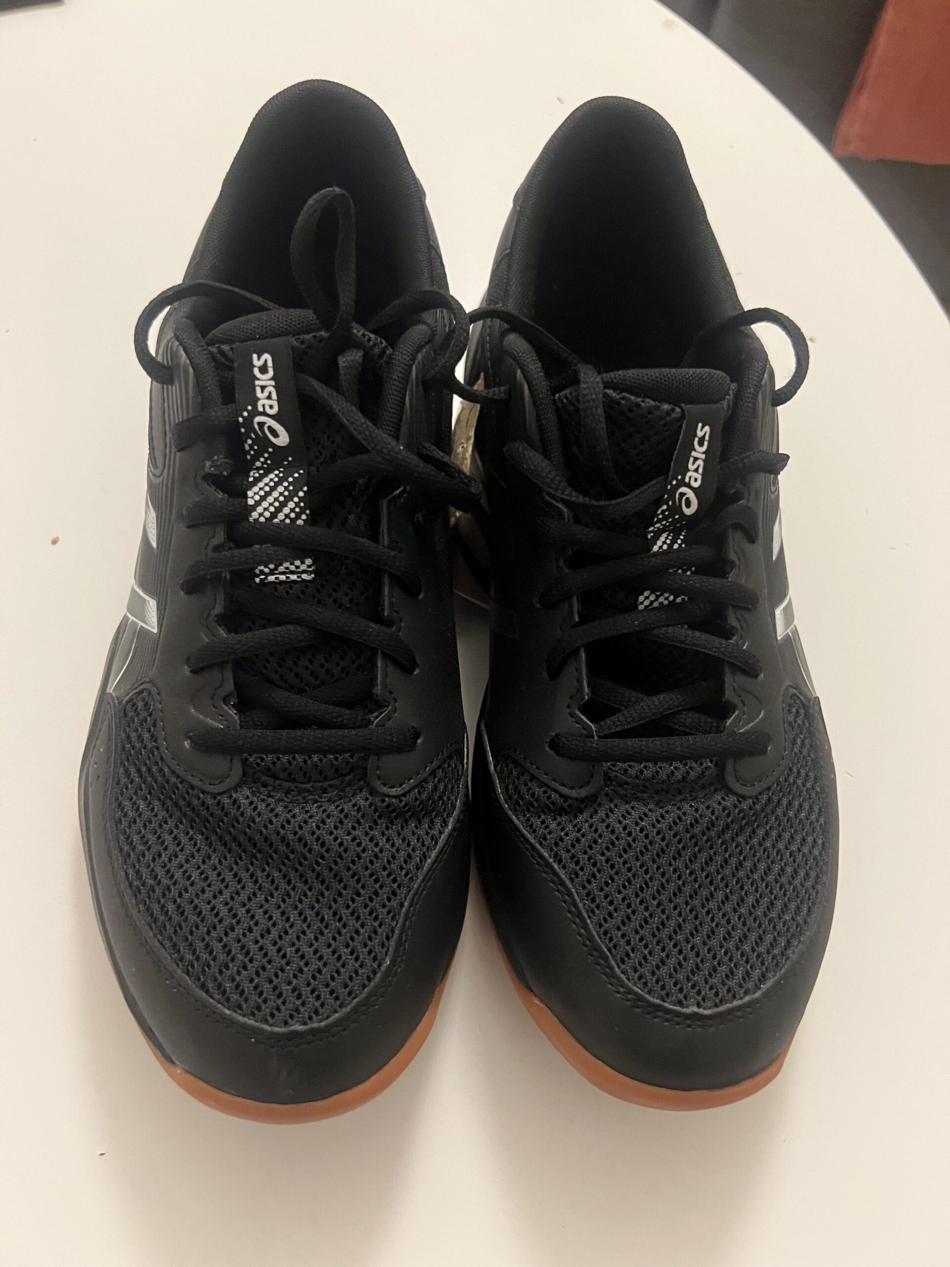 Black and gunmetal ASICS GEL-ROCKET 12 shoes, photographed together from above after eight hours of indoor pickleball