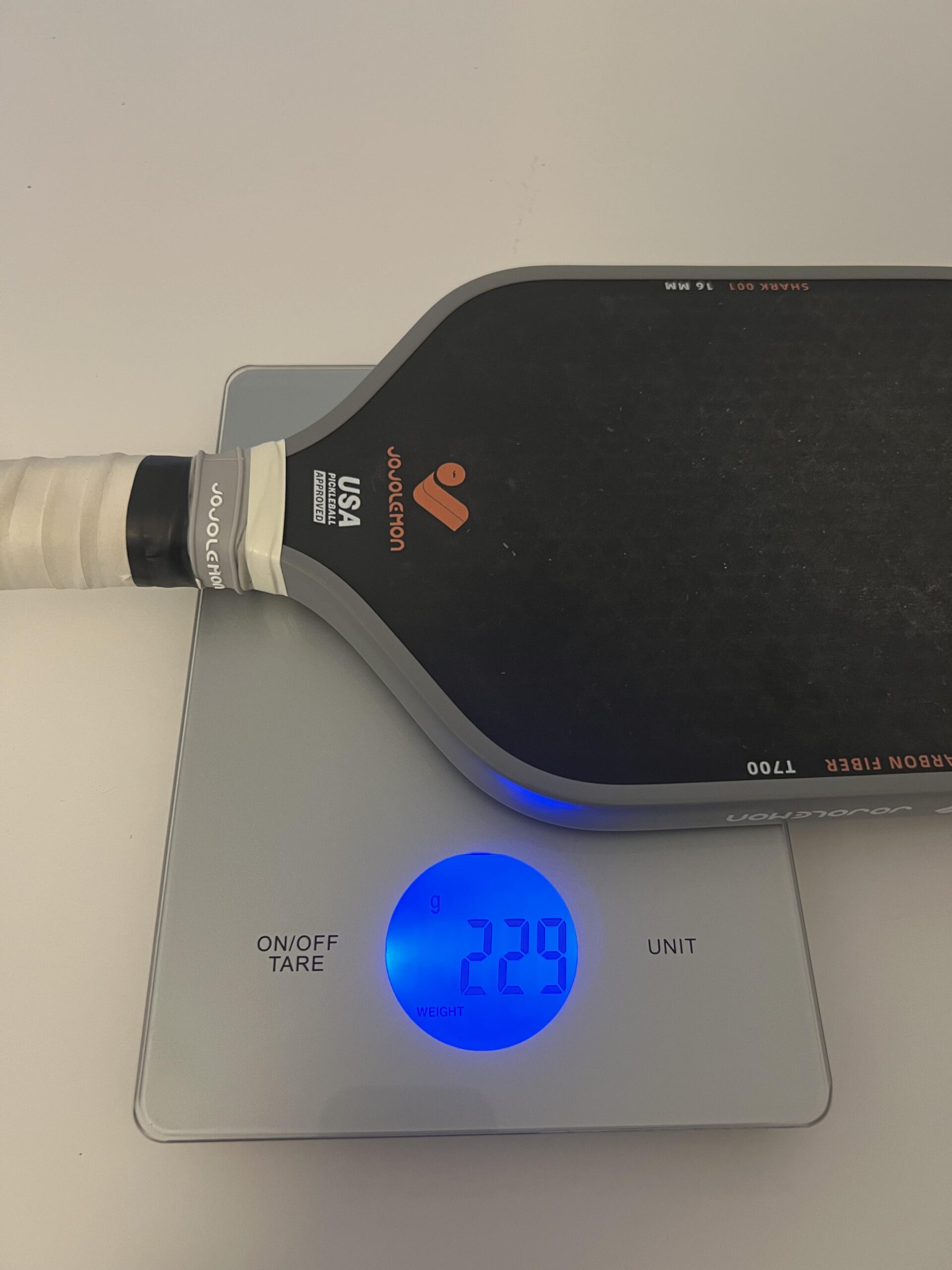 JOJOLEMON Shark 100 pickleball paddle on a digital scale showing 229 grams