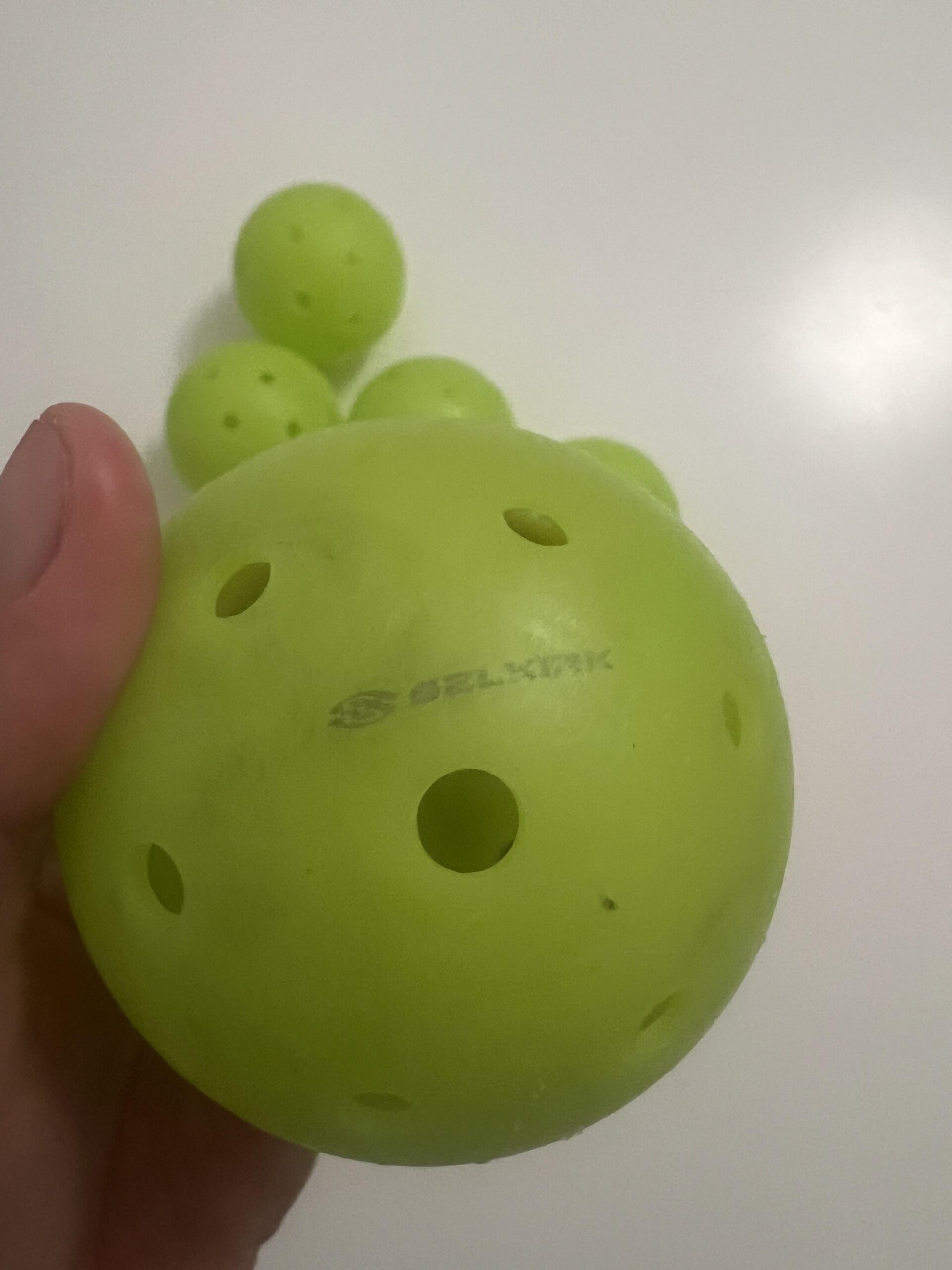 Bola Selkirk Pro S1 pressionada com o polegar mostrando pequena deformação não padronizada