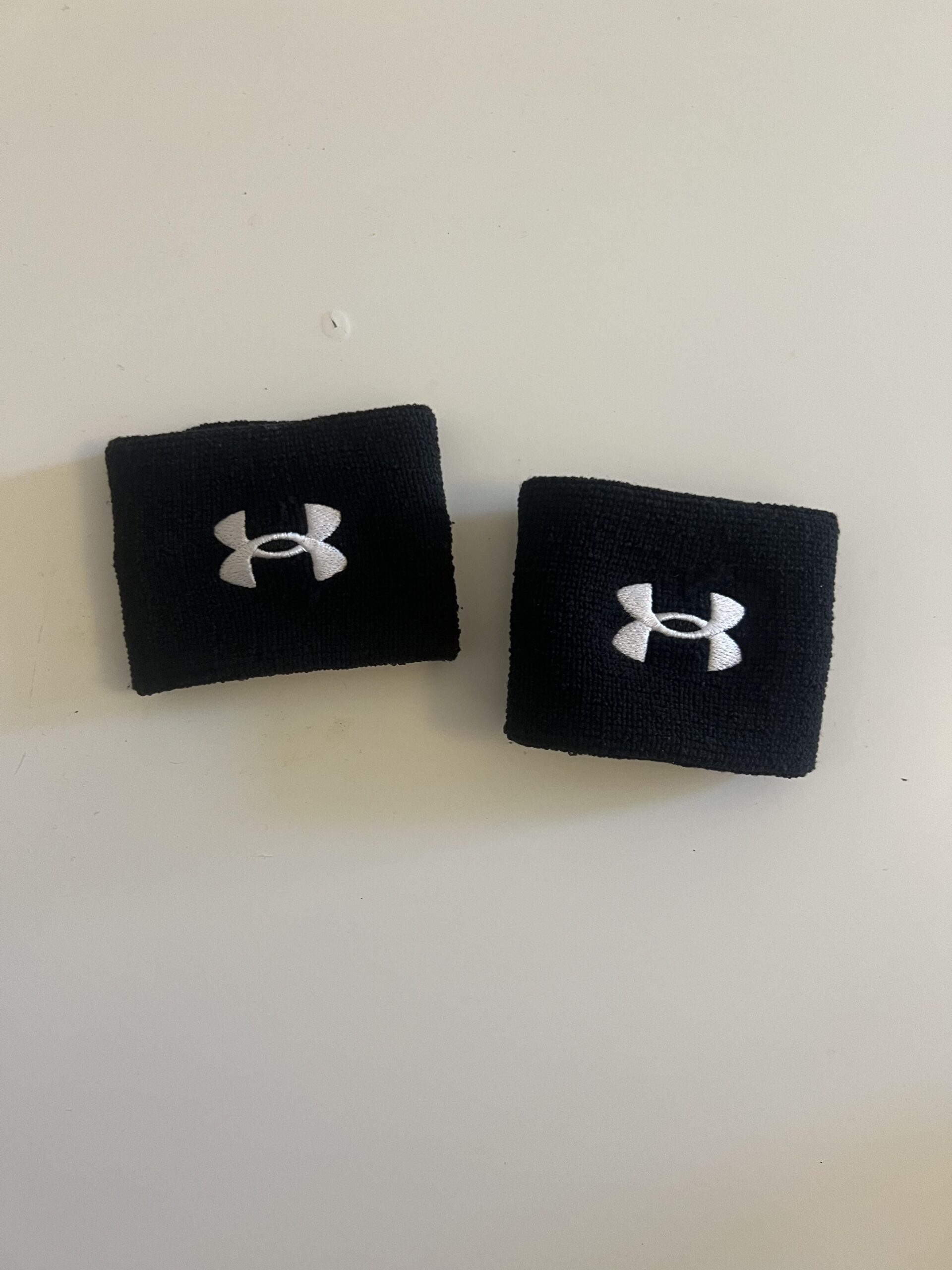 Two black Under Armour 3-inch Performance Wristbands with white embroidered logos