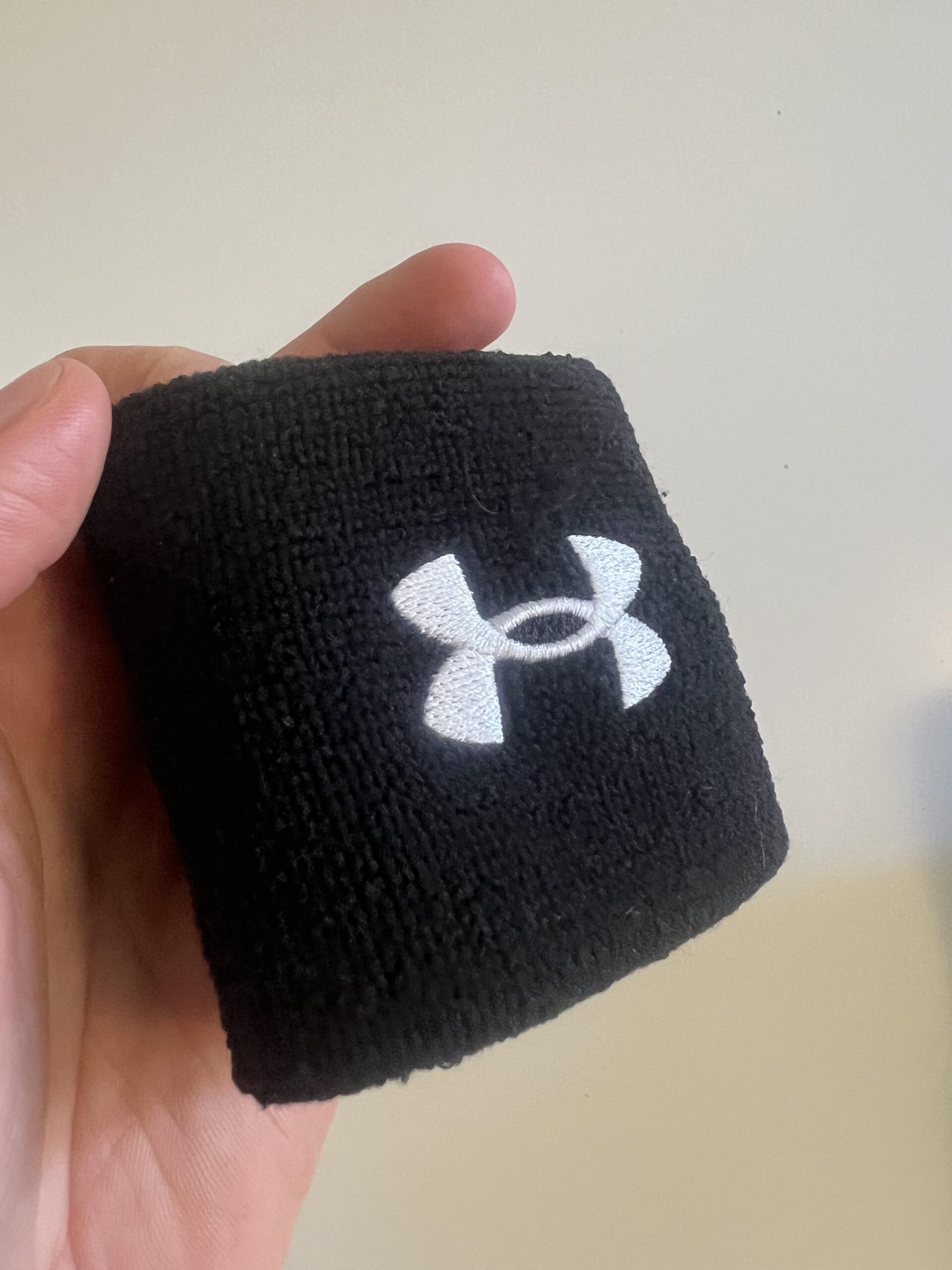 Close-up of the embroidered white Under Armour logo on a black 3-inch Performance Wristband